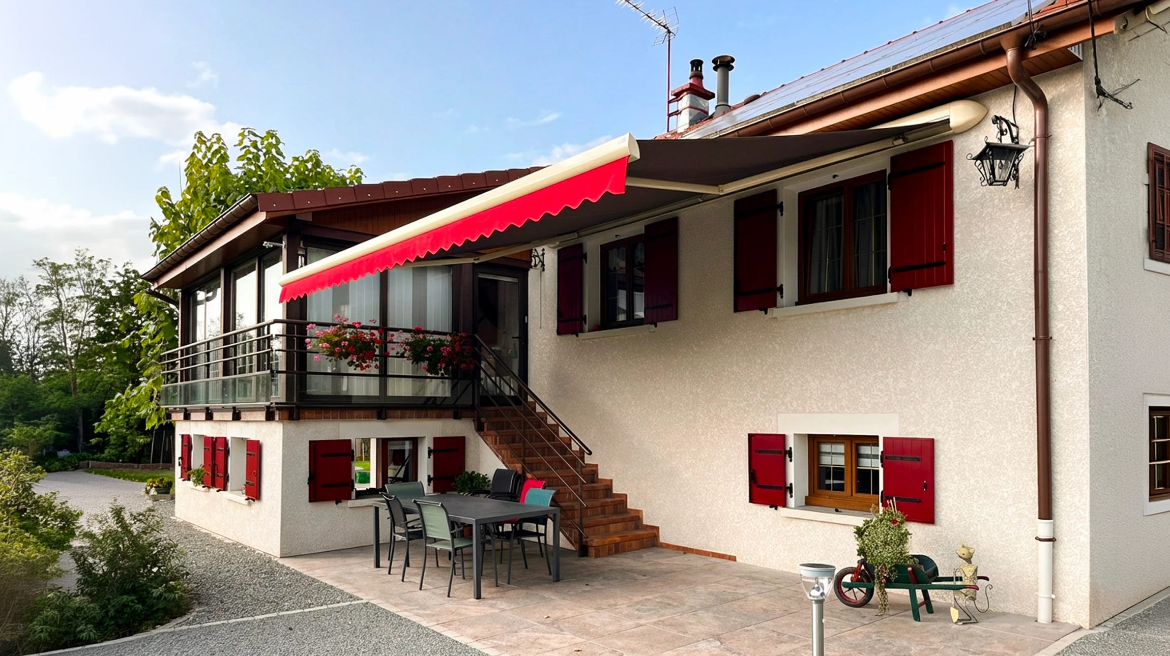 Maison individuelle de style alpin, façade crépi blanc avec volets battants rouge bordeaux