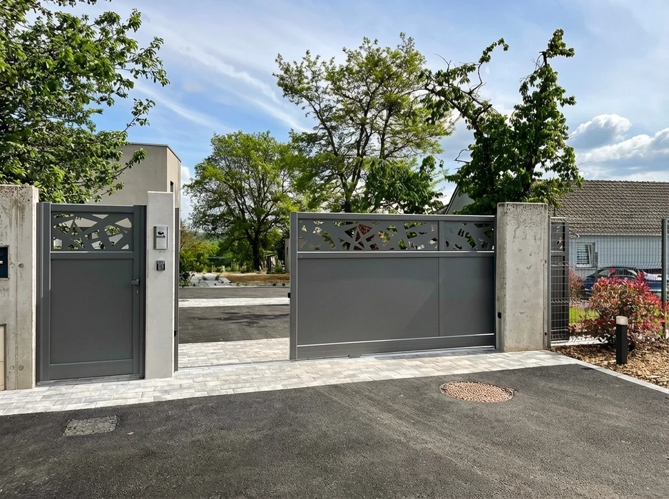 Portail coulissant en aluminium laqué gris anthracite, avec bandeau supérieur ajouré à motifs géométriques découpés au laser