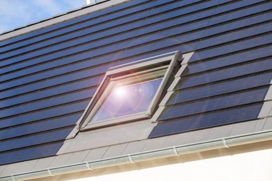 Fen&ecirc;tre de toit sur une maison individuelle avec des tuiles solaires