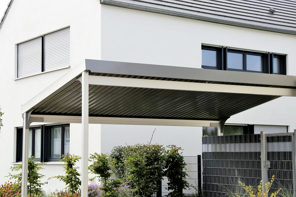 Extérieur résidentiel moderne avec pergola bioclimatique à lames orientables installée devant une maison contemporaine blanche