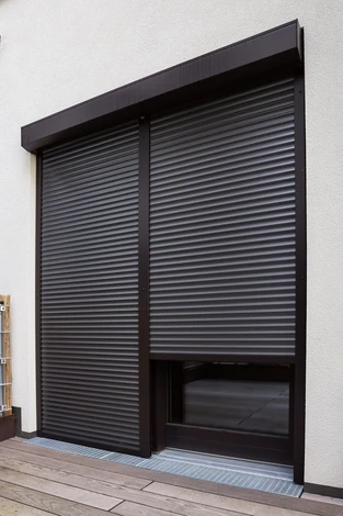 Vue de l'immeuble avec de grandes fenêtres et des volets à rouleaux noirs à l'extérieur
