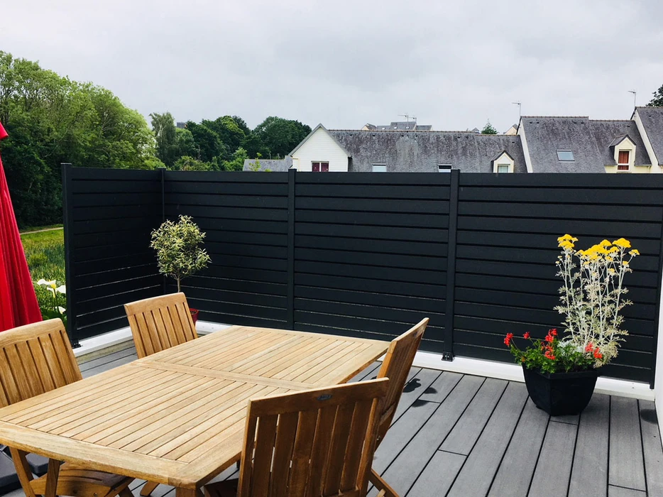 Terrasse extérieure d'une maison en brique avec pergola bioclimatique à lames orientables en aluminium anthracite