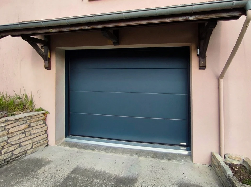 Fa&ccedil;ade ext&eacute;rieure de garage r&eacute;sidentiel moderne avec deux portes sectionnelles en acier gris anthracite ferm&eacute;es