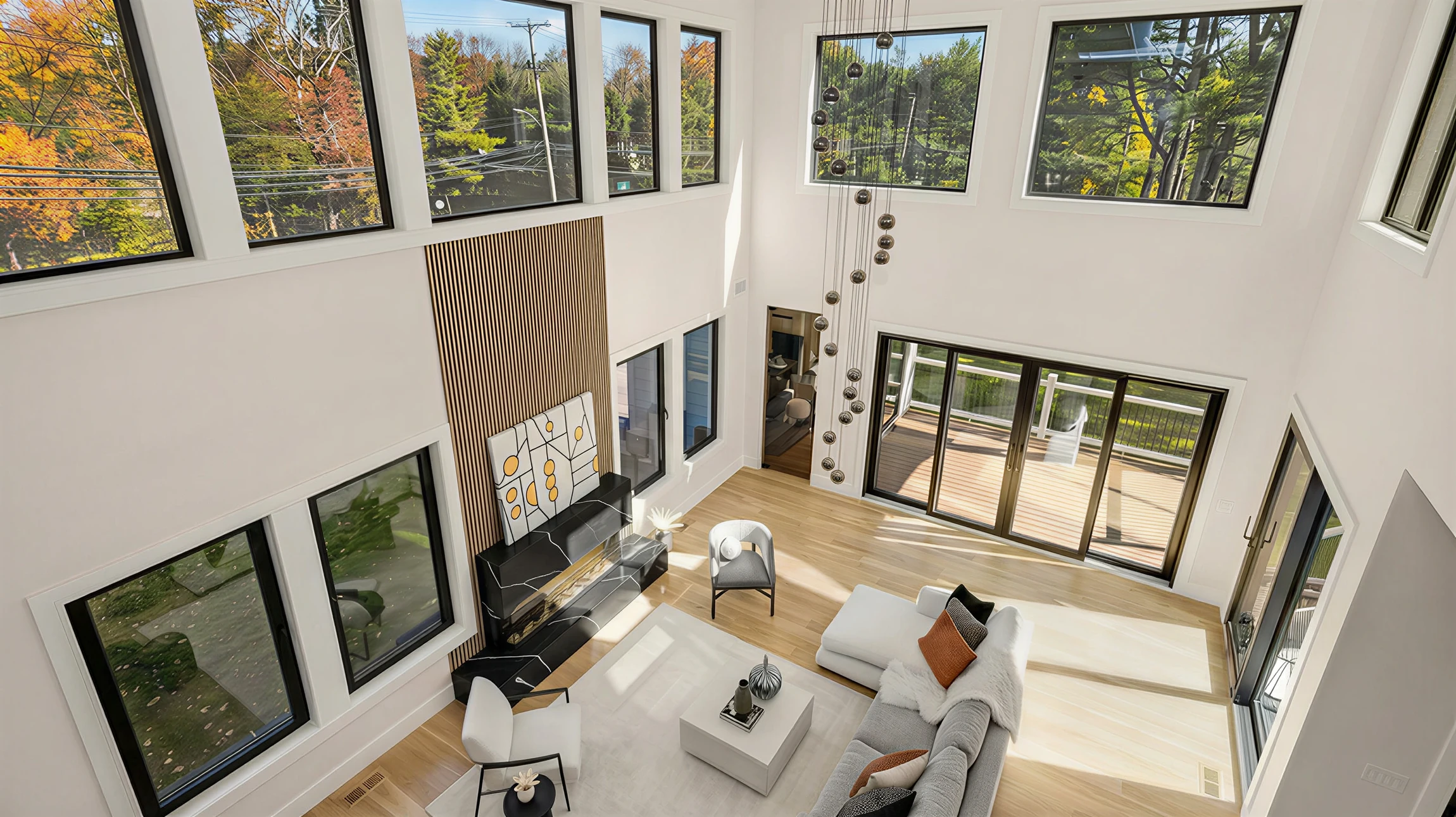 Terrasse moderne d'une maison contemporaine avec deux grandes baies vitrées équipées de volets roulants électriques gris anthracite partiellement abaissés